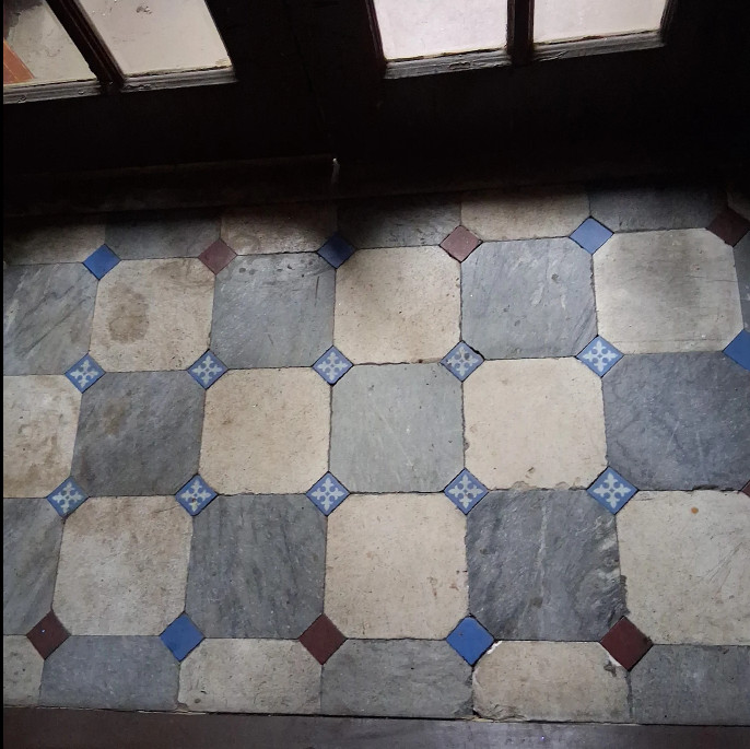 Vestibule floor with octagonal brown stone tiles before professional restoration – dirty and dull surface