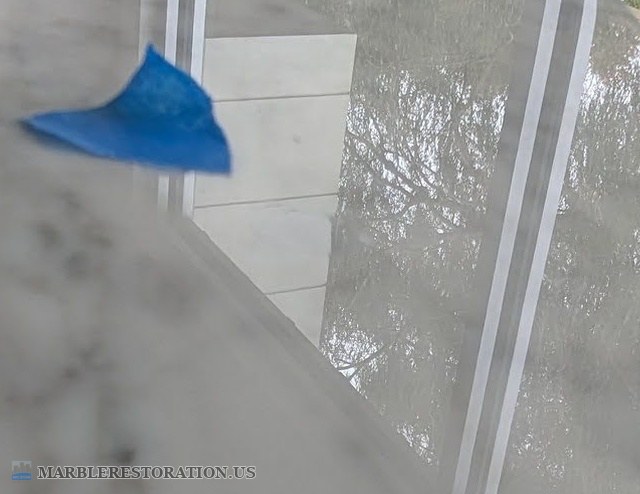 Chipped clear coat on a Saarinen marble table, filled Close-up of the Saarinen marble table edge after the chip in the clear coat was filled, with blue tape marking the spot