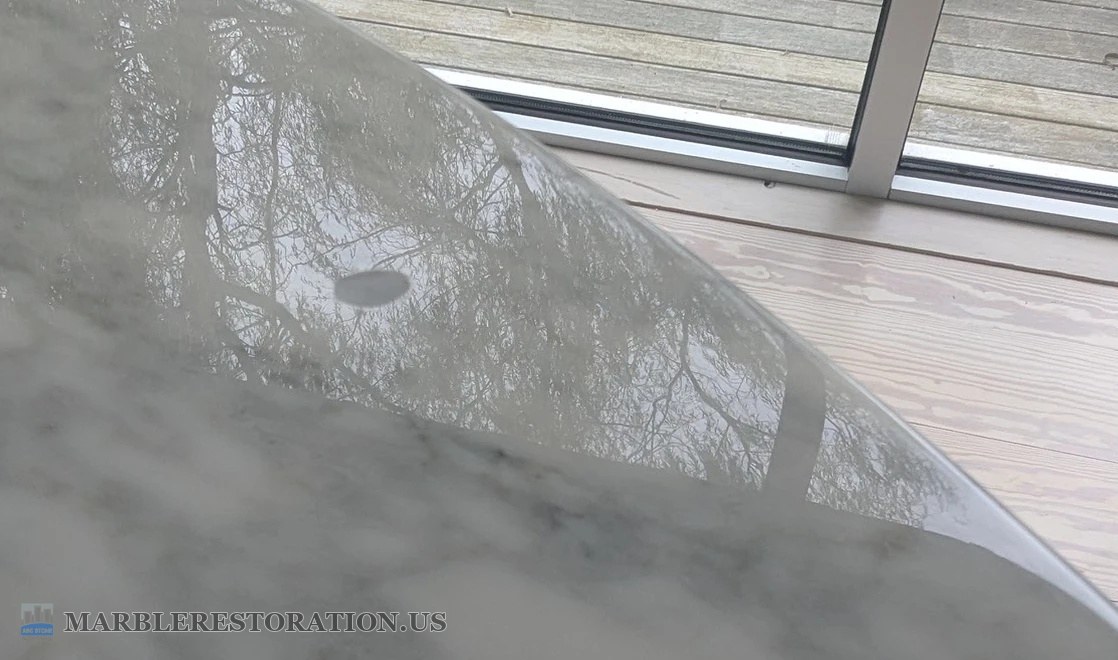 Chipped clear coat on a Saarinen marble table, before Saarinen oval marble table top with a small dark oval in the reflection where the clear coat chipped off