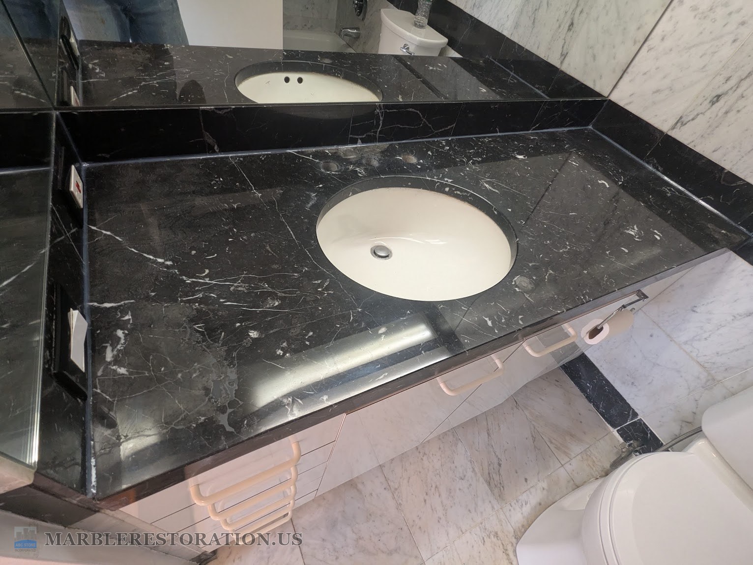 Black marble vanity top polished to a shine after refinishing The same black marble vanity top after polishing, deep black with the ceiling light reflected in it