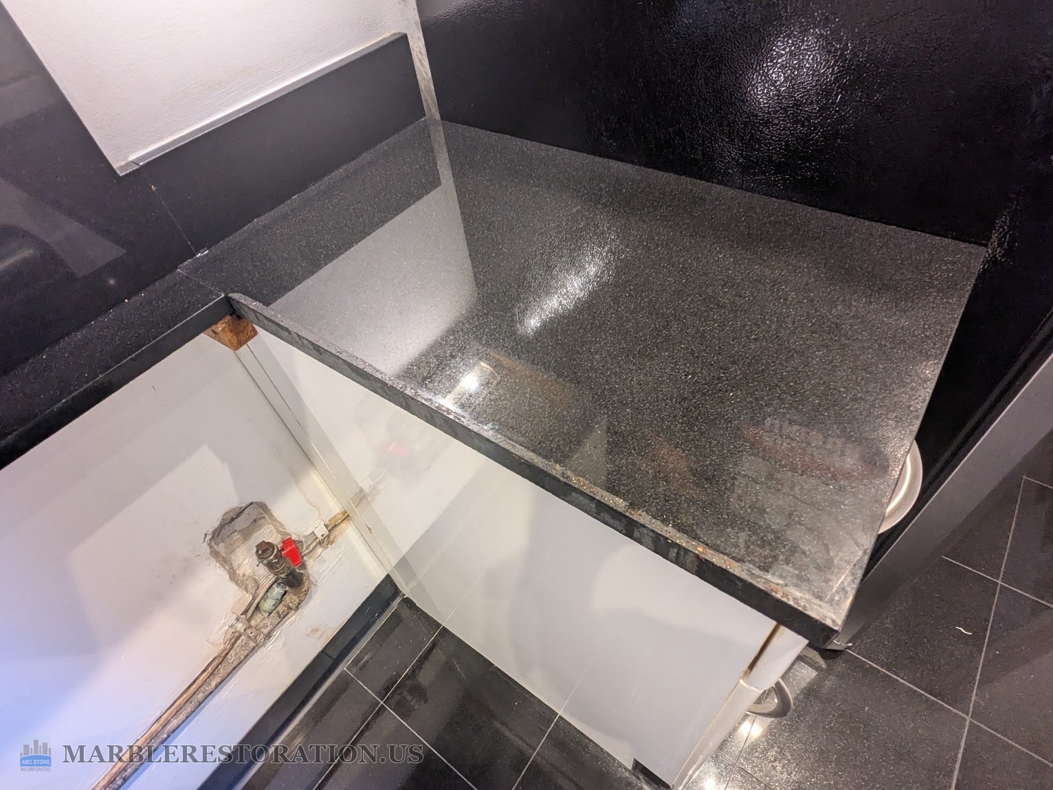 Right granite side at the stove gap, before the cut Right granite countertop side at an empty stove gap, dust on the black granite top, gas valve on the wall to the left