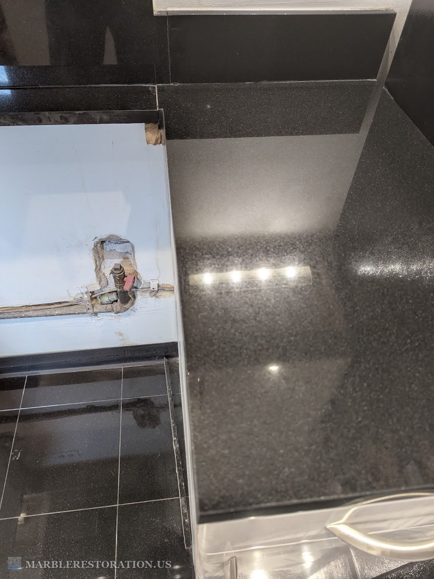 Right granite side cut flush with the wood, after The right granite countertop side after the cut, the edge flush with the wood below it, the black granite top clean and shiny