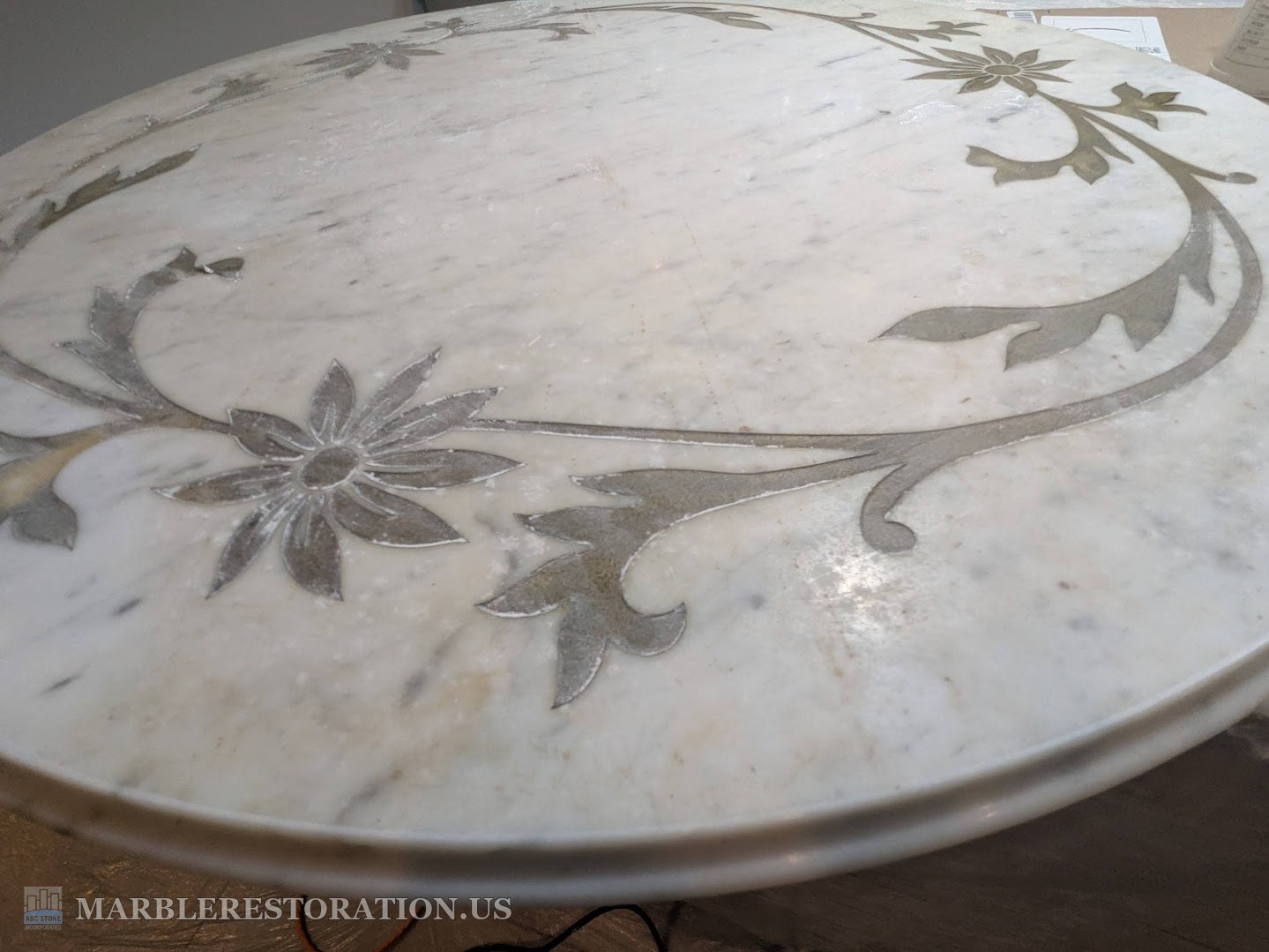 Marble coffee table with gold painted flowers, dull and etched, before Round Carrara marble table top with carved gold painted flowers, the surface dull and etched