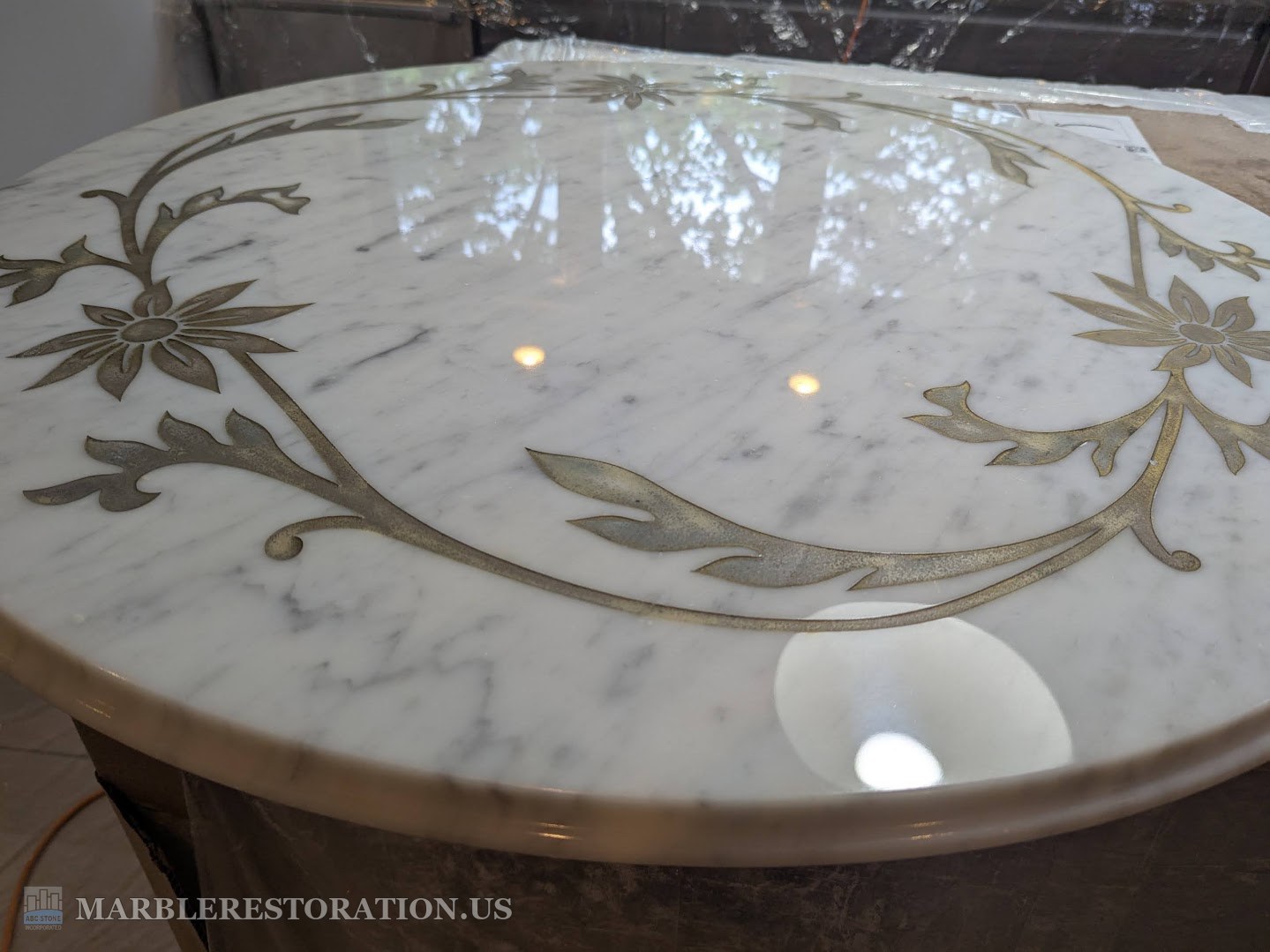 Marble coffee table with gold painted flowers, polished, after Round Carrara marble table top with gold painted flowers, polished to a shine, a window reflected in it