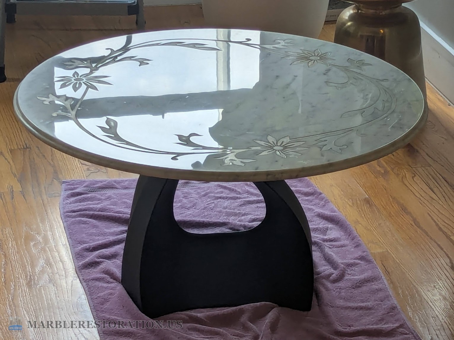 Marble coffee table with gold painted flowers on its new leg, finished Round marble coffee table with gold painted flowers on a black leg, finished, in a living room