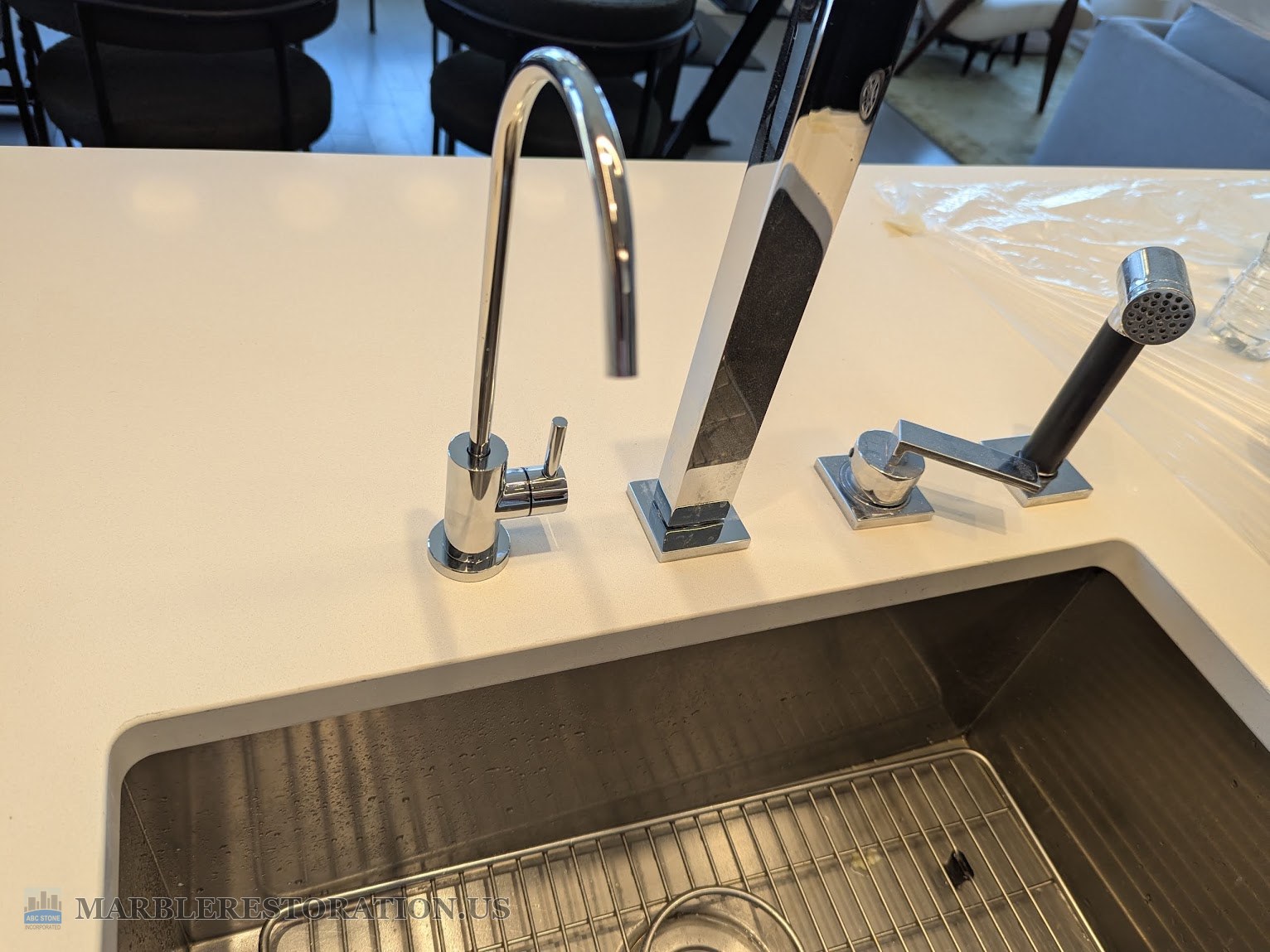 Water filter faucet set in the drilled quartz countertop, after Four chrome fixtures on a white quartz countertop by an undermount sink, the new water filter faucet at the left